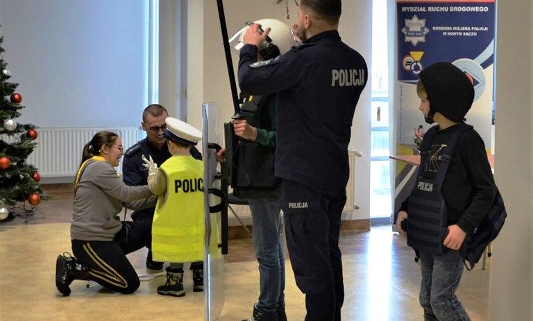 policjanci pomagają dzieciom założyć elementy munduru i policyjnego wyposażenia